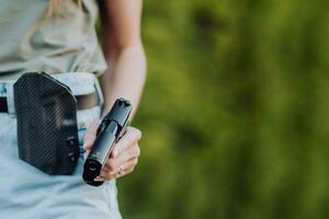 un' ragazza nel denim pantaloncini e con un' pistola nel sua mano pose per un' foto.. avvicinamento foto