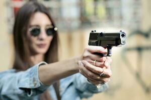 giovane ragazza con un' pistola nel il suo mani spara nel natura foto