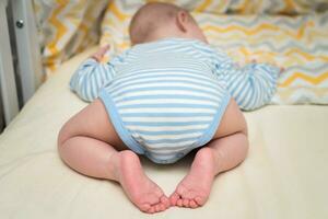 il bambino dorme su il suo stomaco con il suo bottino su. foto