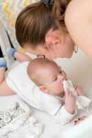 il bambino cerca per lacrima via il protettivo maschera a partire dal sua madre S viso durante il coronovirus e covid-19 pandemia. foto