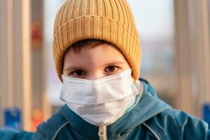 ritratto di un' giovane bambino nel un' medico maschera su il strada durante il coronavirus e covid pandemia - 19 foto