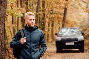 riuscito uomo d'affari viaggiatore su il sfondo di il auto nel il autunno foresta foto