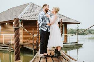 il bellissimo Novelli sposi Abbracciare una persona su il molo.il sposa e sposo essi teneramente Guarda a ogni altro In piedi e posa su il molo. foto