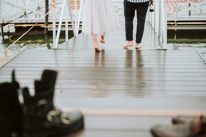 piedi di il Novelli sposi su il sfondo di il molo.il sposa e sposo partire a piedi nudi lungo il molo. foto