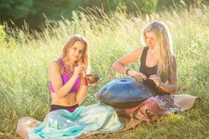 giovane ragazze giocare e cantare su il musicale strumento padella. pratica meditazione a tramonto foto