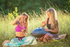 giovane donne giocare e cantare su il musicale strumento padella. pratica meditazione a tramonto foto