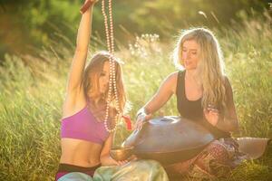 giovane ragazze giocare e cantare su il musicale strumento padella. pratica meditazione a tramonto foto