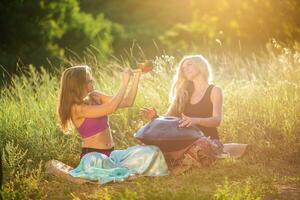 giovane donne giocare e cantare su il musicale strumento padella. pratica meditazione a tramonto foto