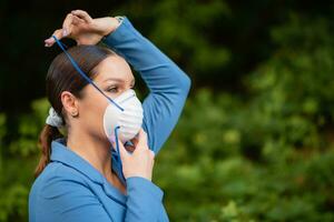 bellissimo ragazza mette un' medico maschera su sua viso su il natura. coronavirus e covid-19 protezione foto