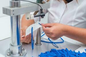 il ragazza lavori nel un' fabbrica per il produzione di medico maschere con nanofibra e saldare loop con ultrasuono su un' macchina. coronavirus e covid-19 protezione.primo piano. foto