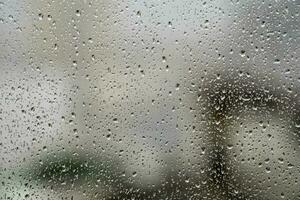 finestra bicchiere con gocce di pioggia mostrando sfocato città nel il sfondo foto