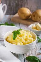 fresco schiacciato patate e basilico le foglie nel un' ciotola su il tavolo verticale Visualizza foto