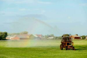 un' trattore spruzzatura acqua su un' campo foto