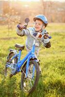 carino bambino è guida un' bicicletta su un' soleggiato giorno a tramonto foto