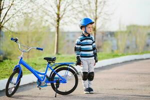 carino bambino nel casco e protezione sta vicino il suo bicicletta foto