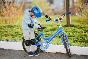 un' bambino nel un' casco impara per cavalcata un' bicicletta su un' soleggiato giorno a tramonto foto