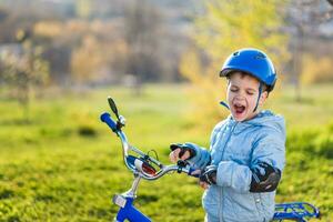 un' bambino nel un' casco impara per cavalcata un' bicicletta su un' soleggiato giorno a tramonto foto