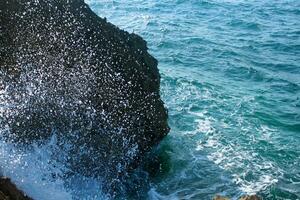 mare acqua spruzzo su roccioso riva foto