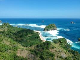 ungapan spiaggia è nel est Giava, Indonesia, colline e tropicale impianti con visualizzazioni di il blu mare e molto chiaro cieli. foto