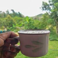 mano Tenere un' tazza di latteo tè isolato su natura sfondo. foto