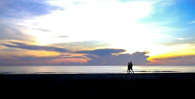 silhouette di un' coppia a piedi su il spiaggia nel il mattina foto