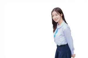 bellissimo alto scuola asiatico alunno ragazza nel scuola uniforme sta e sorrisi felicemente con bretelle su sua denti mentre lei sembra a telecamera isolato su bianca sfondo. foto