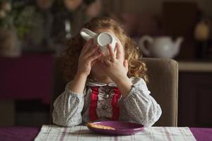 la bambina beve il tè da una tazza grande foto