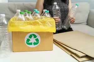 casa riciclare eco verde zero concetto donna lancio vuoto plastica bottiglia nel raccolta differenziata bidone con giallo spazzatura borse a casa. foto