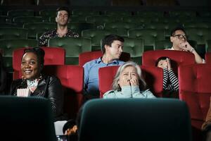 vario persone nel Teatro. anziano asiatico donna e multirazziale pubblico siamo impaurito di Guardando thriller e orrore cinema, spaventato insieme di film, e divertimento stile di vita con film arte mostrare. foto