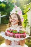 sdentato ragazza ride felicemente. bambino detiene un' compleanno torta con un' candela nel modulo di 8 e iscrizione contento compleanno. festeggiare eventi all'aperto nel parco. foto
