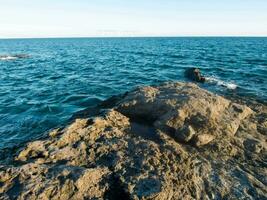 un' roccioso litorale con acqua e rocce nel il sfondo foto