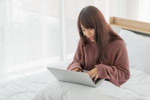 donne asiatiche che lavorano con il computer portatile sul letto