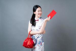 la donna asiatica indossa un abito tradizionale cinese con una busta rossa o un pacchetto rosso foto