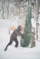 un' uomo portato un' Natale albero in il suo cortile durante un' tempesta di neve. foto