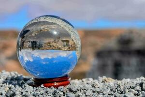 un' bicchiere palla con un' blu cielo e un' montagna nel il sfondo foto