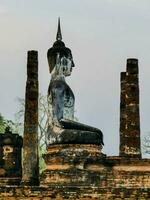 un' Budda statua si siede su superiore di un' mattone parete foto