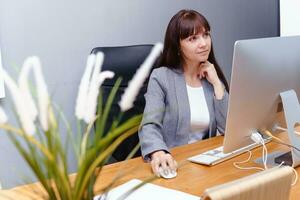 un' brunetta donna a un' computer nel il posto di lavoro. attività commerciale concetto. foto