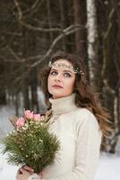 bellissimo sposa nel un' bianca vestito con un' mazzo nel un' innevato inverno foresta. ritratto di il sposa nel natura foto