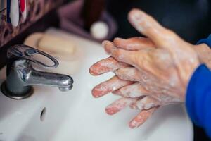 anziano uomo lavaggi mani con sapone. protezione contro virus e batteri infezione. disinfezione di mani con acqua. covid19, coronavirus pandemia foto