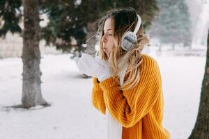 adolescente bionda nel un' giallo maglione al di fuori nel inverno. un' adolescenziale ragazza su un' camminare nel inverno Abiti nel un' nevoso foresta foto