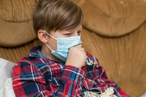 ragazzo nel protettivo medico maschera bugie nel letto e tosse. ragazzo bambino è malato. bambino con influenza o freddo protetta a partire dal virus tra pazienti con coronavirus. foto