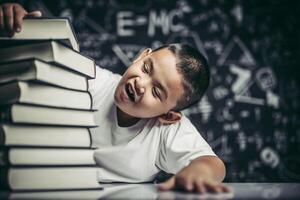 un ragazzo con gli occhiali seduto in classe a contare i libri foto