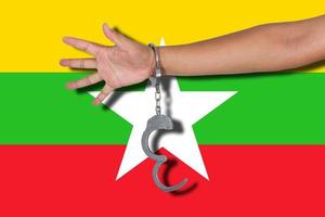 manette con la mano sulla bandiera del myanmar foto