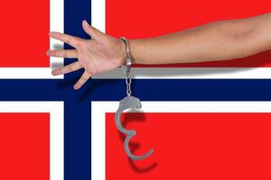 manette con la mano sulla bandiera della norvegia foto