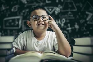 i ragazzi con gli occhiali scrivono libri e pensano in classe foto