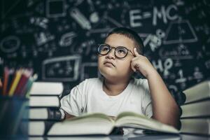 i ragazzi con gli occhiali scrivono libri e pensano in classe foto