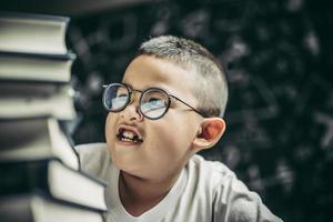 un ragazzo con gli occhiali seduto in classe a contare i libri foto