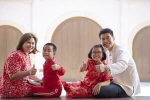 asiatico famiglia indossare rosso Cinese completo da uomo mano cartello va bene contro Cinese parete sfondo foto