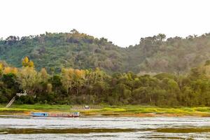 un' barca è in viaggio giù il fiume nel davanti di un' foreste collina foto