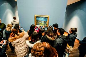 un' gruppo di persone guardare a un' pittura nel un arte Museo foto